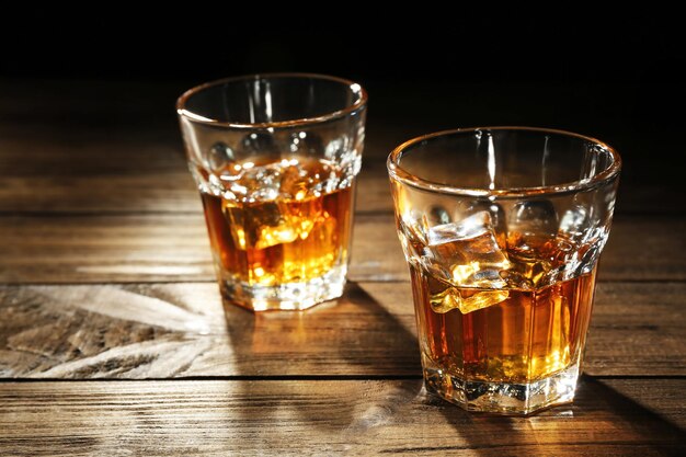 Glasses of whisky on wooden table closeup