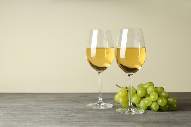 Glasses of white wine and grape on gray textured table