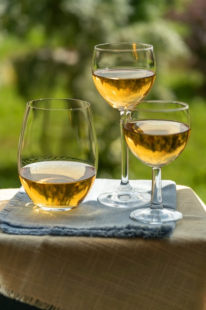 Glasses of white wine over green garden background,outdoor.