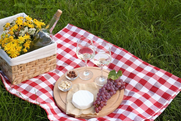 Photo glasses of white wine and snacks for picnic served on blanket outdoors