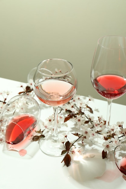 Glasses of wine and cherry flowers on white table