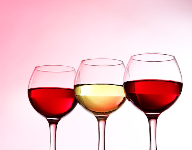 Glasses of wine on light pink tone