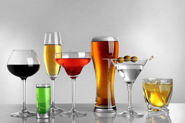 Glasses of wine and spirits on light background