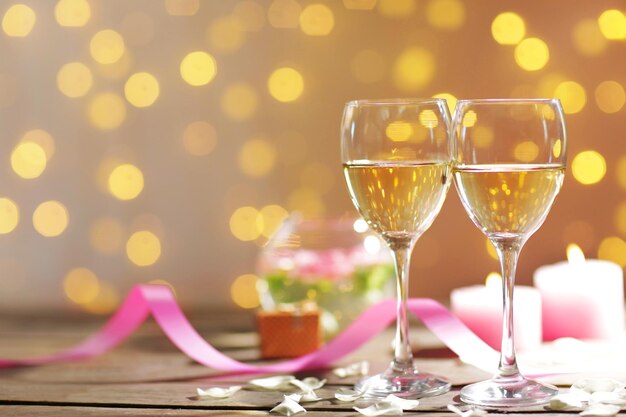 Glasses of wine, white roses and candles, on blurred background