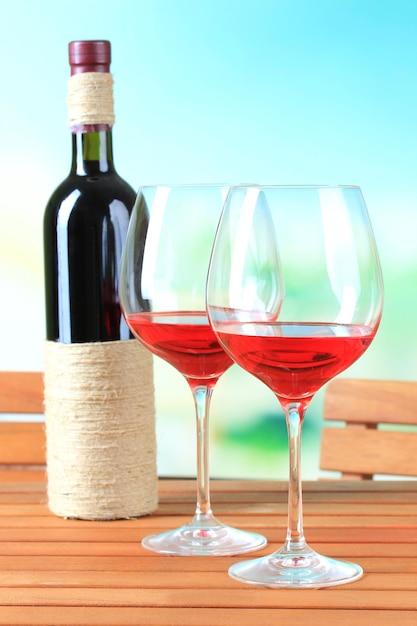 自然の背景に木製のテーブルにワインのグラス