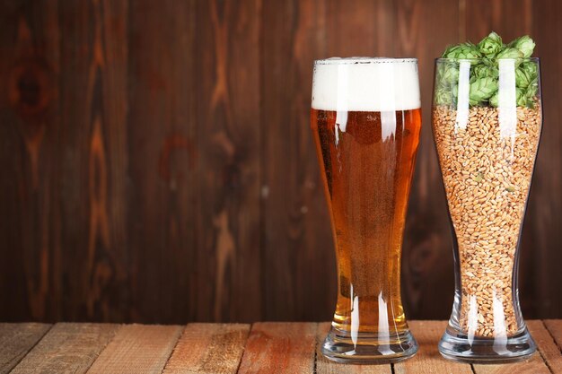 Glasses with beer hops and malts on wooden background