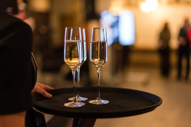 glasses with champagne on a tray at the waiter