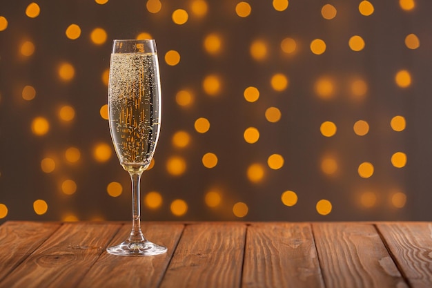 Glasses with champagne on a wooden background against a bokeh background of lights