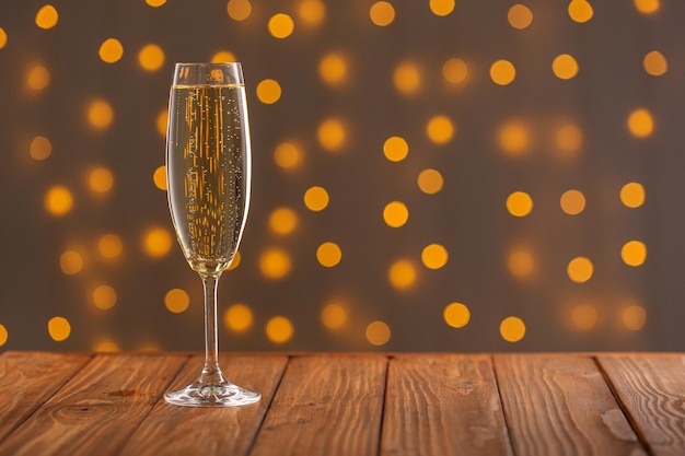 Glasses with champagne on a wooden background against a bokeh background of lights