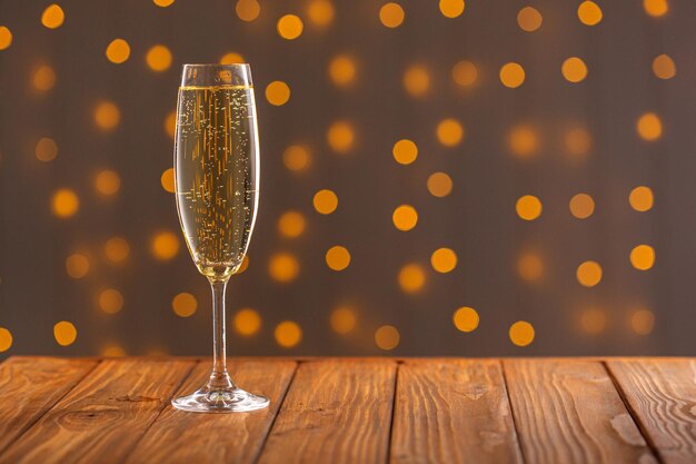 Glasses with champagne on a wooden background against a bokeh background of lights