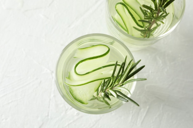 Glasses with cucumber water on white surface