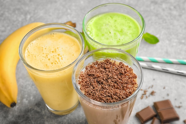 Glasses with different protein shakes on table closeup