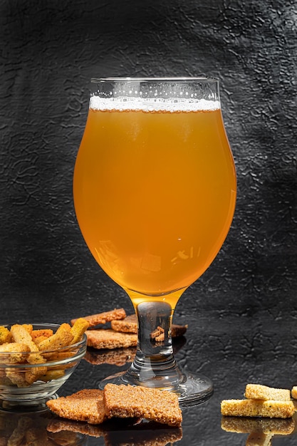 Glasses with different types of craft beer on a wooden bar In glasses and bottles Nuts and crackers on the table On a dark background