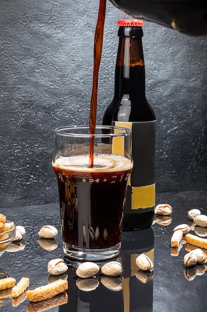 Стаканы с разными сортами крафтового пива на деревянном баре В стаканах и бутылках Орехи и крекеры на столе На темном фоне