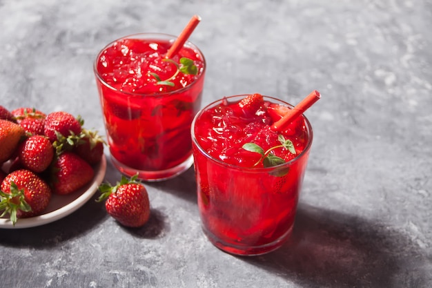 Glasses with fresh homemade strawberry sweet iced tea or cocktail, lemonade with mint. Refreshing cold drink. Summer party.