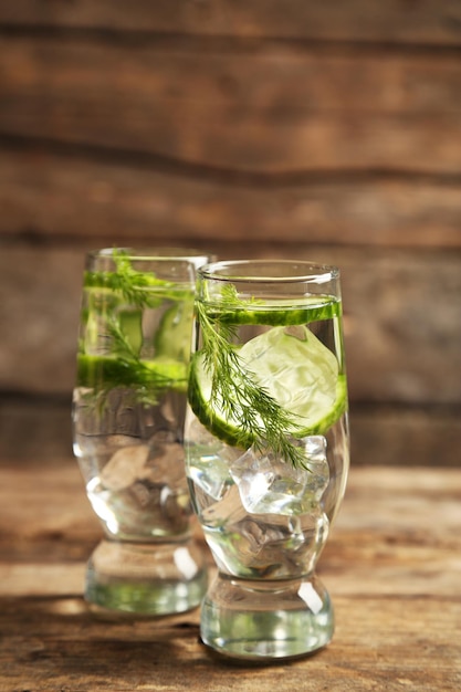 Glasses with fresh organic cucumber water on wooden table