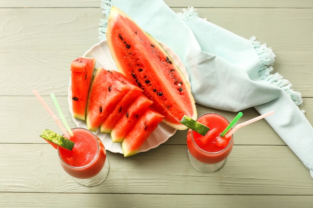 Glasses with fresh watermelon juice on color wooden background