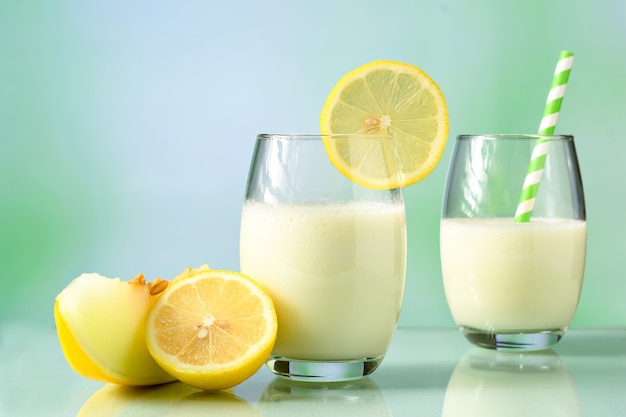 Bicchieri con succo di melone al latte e limone di sicilia su superficie riflettente