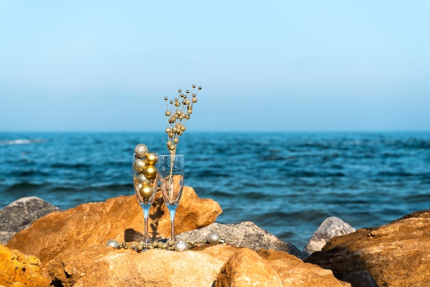海沿いの岩の多いビーチで新年のお祝いを飾るグラス。コピースペース