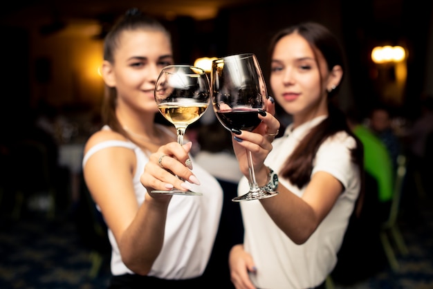 Glasses with red and white guilty in the hands of beautiful girls dressed in white blouses