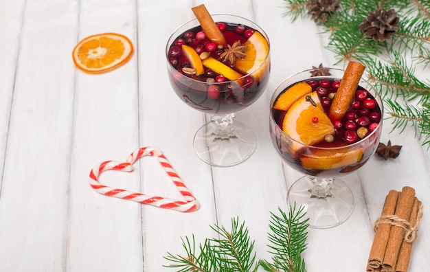 Glasses with traditional Christmas drink with cranberry on white wooden background