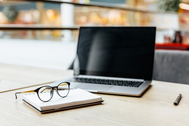 Glasses at the workplace in the office near the laptop and notepad. Business hours