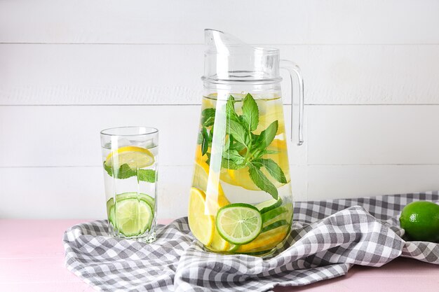 Glassware of fresh lime lemonade on color table