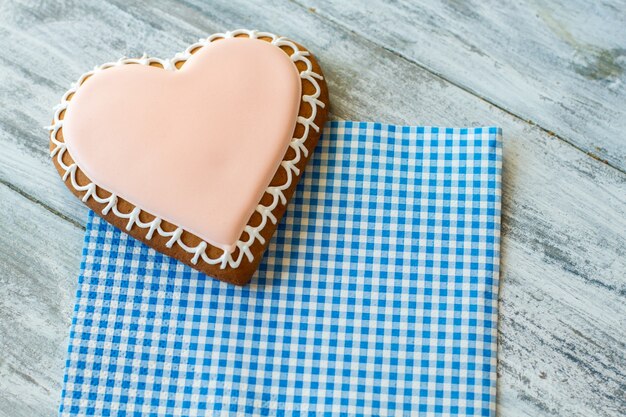 Glazed biscuit shaped as heart. Cookie on checkered napkin. Dessert for those in love. Find ways to show feelings.