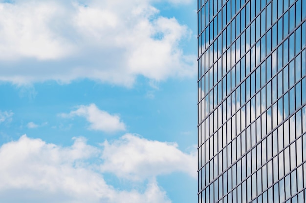 雲と青い空を背景に高層ビルのガラス張りのファサード