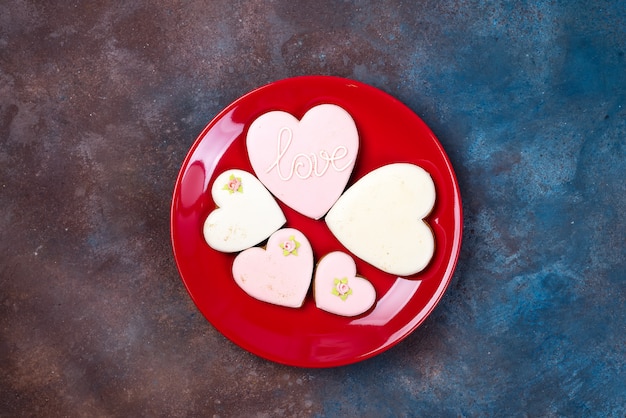 Foto biscotti a forma di cuore smaltato sul piatto rosso. buon san valentino