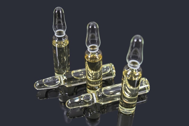 Foto glazen ampullen met lichtgeel medicijn op een donkere achtergrond