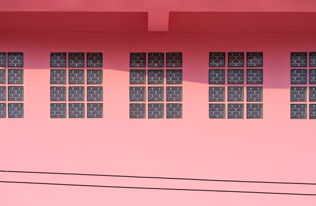Glazen bakstenen blokken op roze betonnen muur van vintage huis met zonlicht en schaduw op het oppervlak