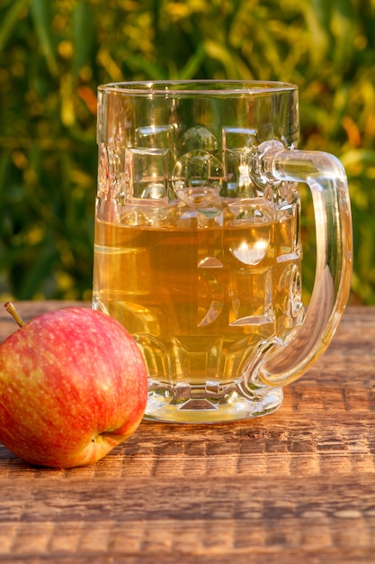 Glazen beker appelcider en geoogste appels op houten planken