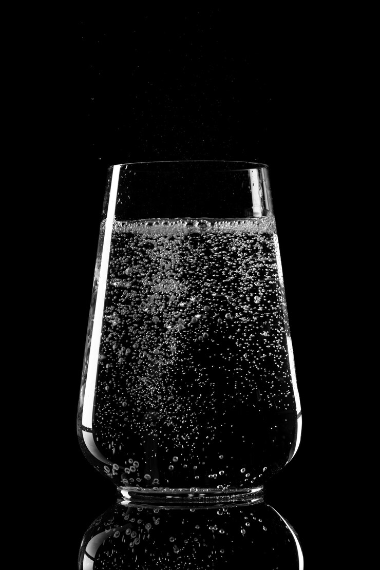 Glazen beker met puur mineraalwater op een zwarte achtergrond