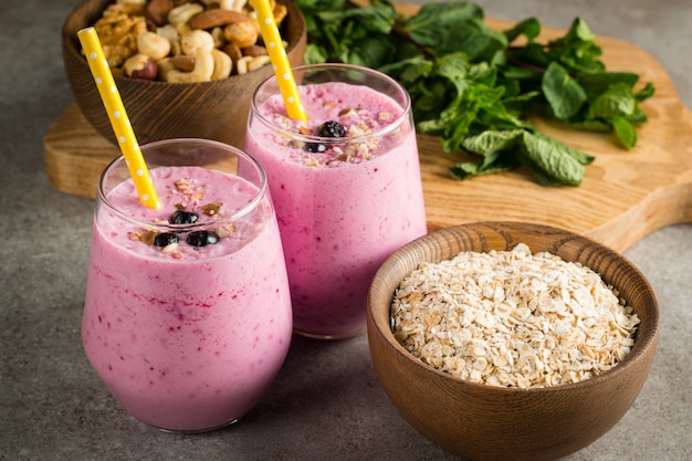 Glazen bessen smoothie met noten, munt, bosbessen, frambozen en yoghurt op houten tafel. Gewichtsverlies en dieet.