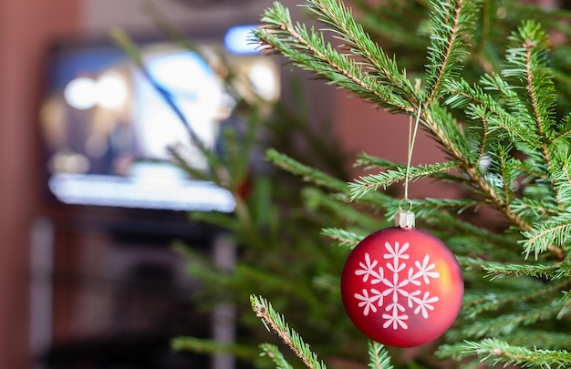 Glazen bol op takjes kerstboom en tv-toestel