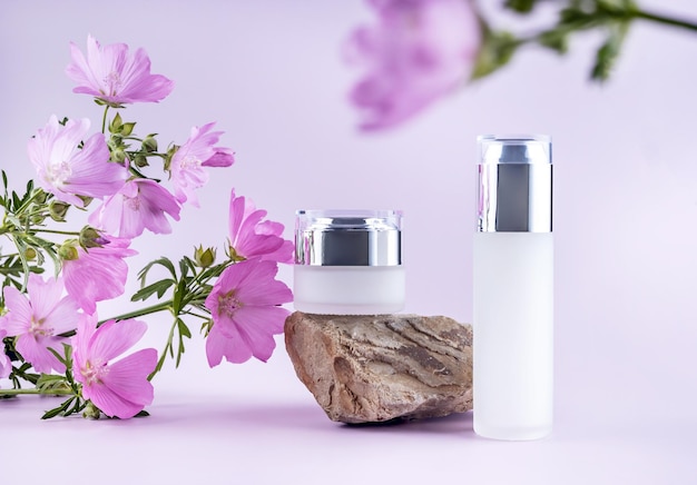 Glazen containers voor cosmeticasteen en bloemen op een paarse achtergrond