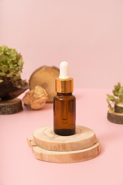 Glazen druppelflesje met cosmetische olie of serum bij herfstscènecompositie met podium