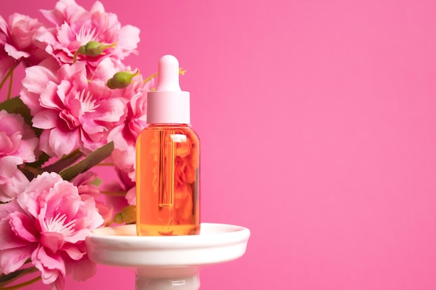 Glazen druppelflesje op podium met bloemen op roze achtergrond Cosmetische containermodel