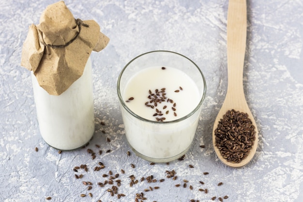 Glazen fles en glas yoghurt met lijnzaad, houten lepel met lijnzaad