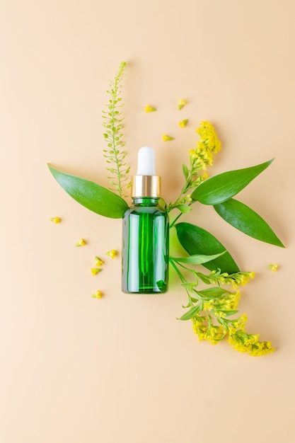 Glazen fles met cosmetische oliën met gele lentebloemen Flessen met serum of etherische olie op een beige achtergrond Cosmetische producten