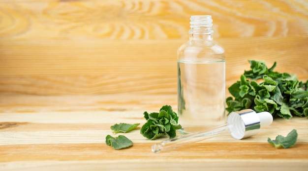 Glazen fles met muntblaadjes op een houten tafel