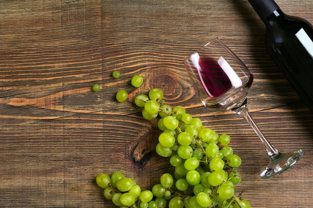 Glazen fles rode wijn en druif op een houten tafel