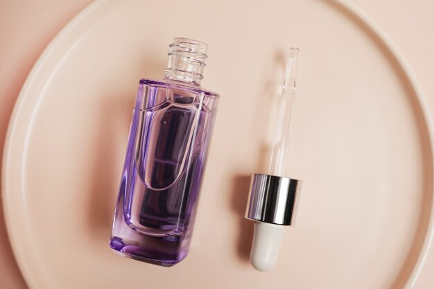 Glazen fles voor cosmetica, natuurlijke geneeskunde, etherische oliën of andere vloeistoffen op roze plaatscène