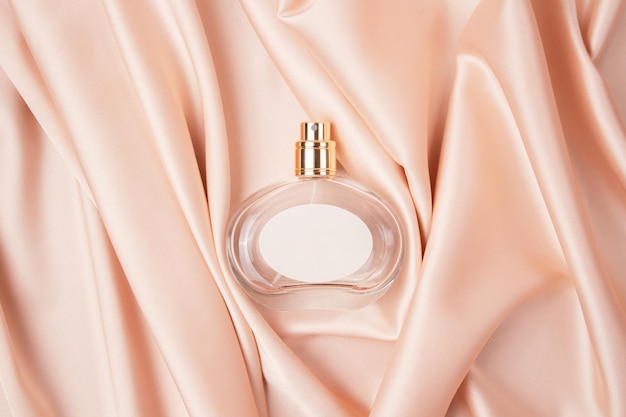 Glazen flesje parfum zonder deksel op een achtergrond van roze zijde het concept van dure parfum en cosmetica