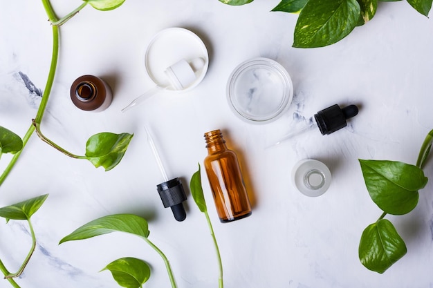 Glazen flessen en pot voor natuurlijke cosmetica op een witte marmeren achtergrond