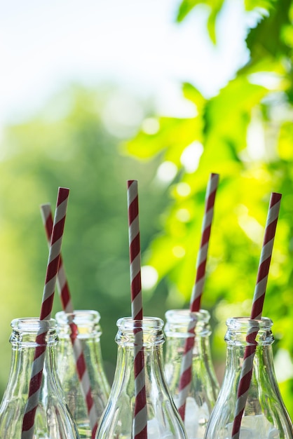 Foto glazen flessen met rietjes over de zonnige achtergrond