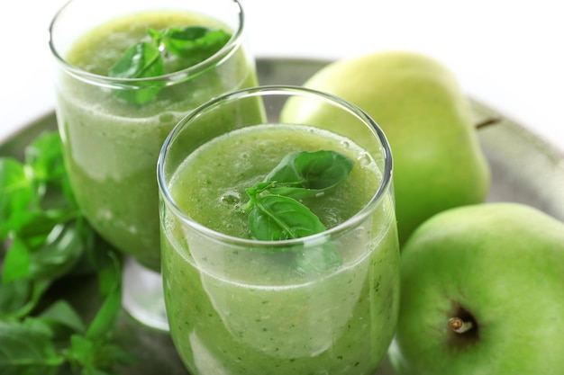 Glazen groen gezond sap met basilicum en appels op metalen dienblad close-up