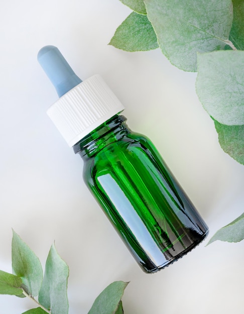 Glazen groene fles en groene eucalyptusbladeren