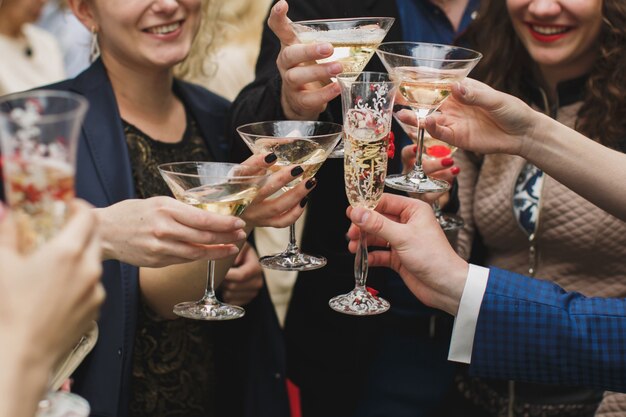 Glazen houden en handen die, gelukkig feestelijk ogenblik, het concept van de luxeviering roosteren. Rammelende glazen champagne in handen